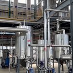 Stainless steel conical-bottom receiver tanks with blue pump motors in pharmaceutical extraction system