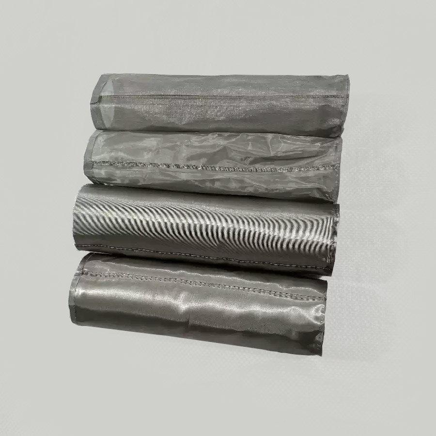 Close-up of four rolled stainless steel mesh filter cylinders stacked horizontally showing different surface weaves and side seams