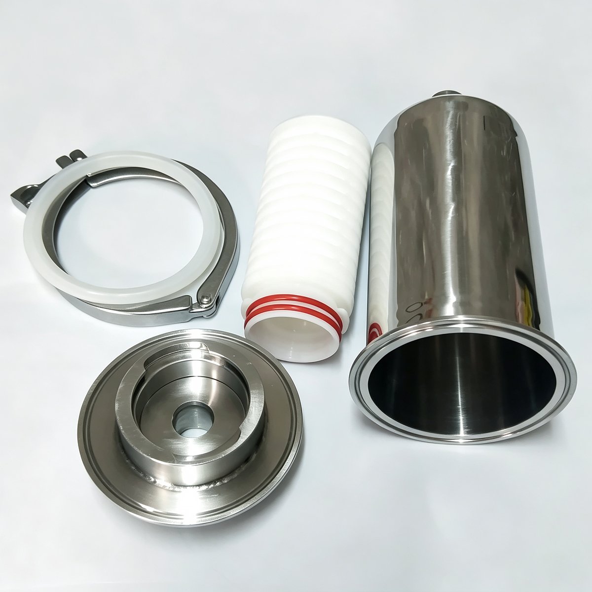 Disassembled stainless steel sanitary filter housing with pleated filter cartridge, clamp and end cap