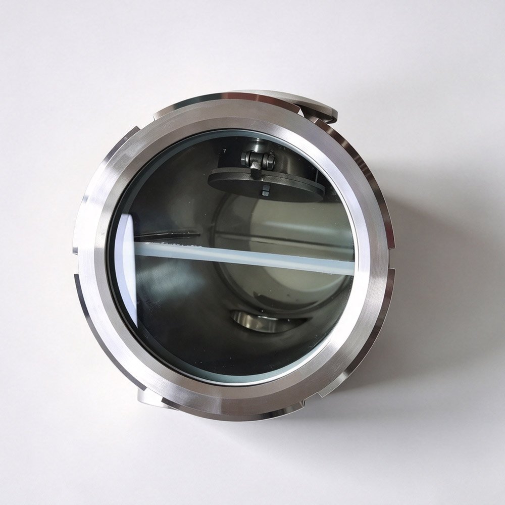 Close-up view of sanitary air break sight glass showing internal stainless steel flap and flow path